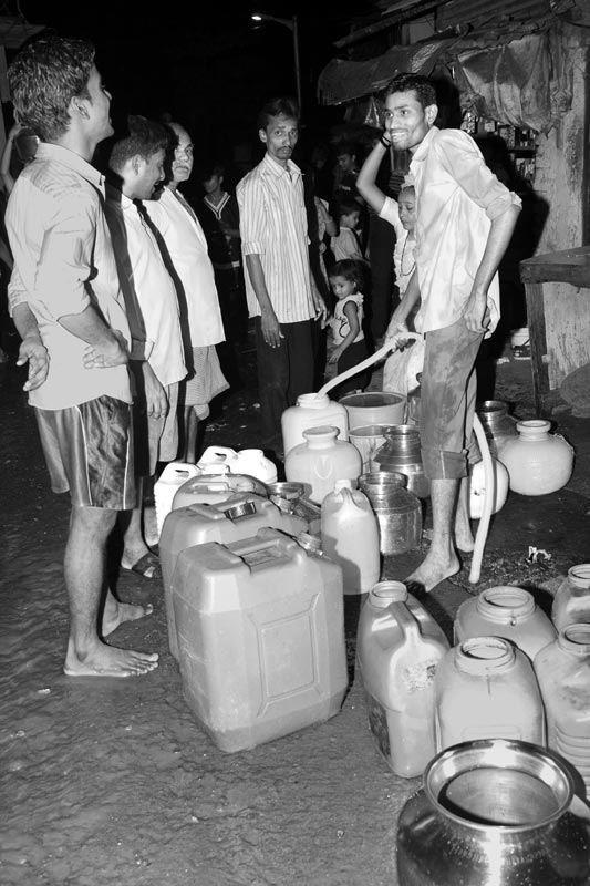 Men and Drinking Water Procurement - Helping with filling up drinking water containers at a group connection late in the night in Mumbai, Maharashtra